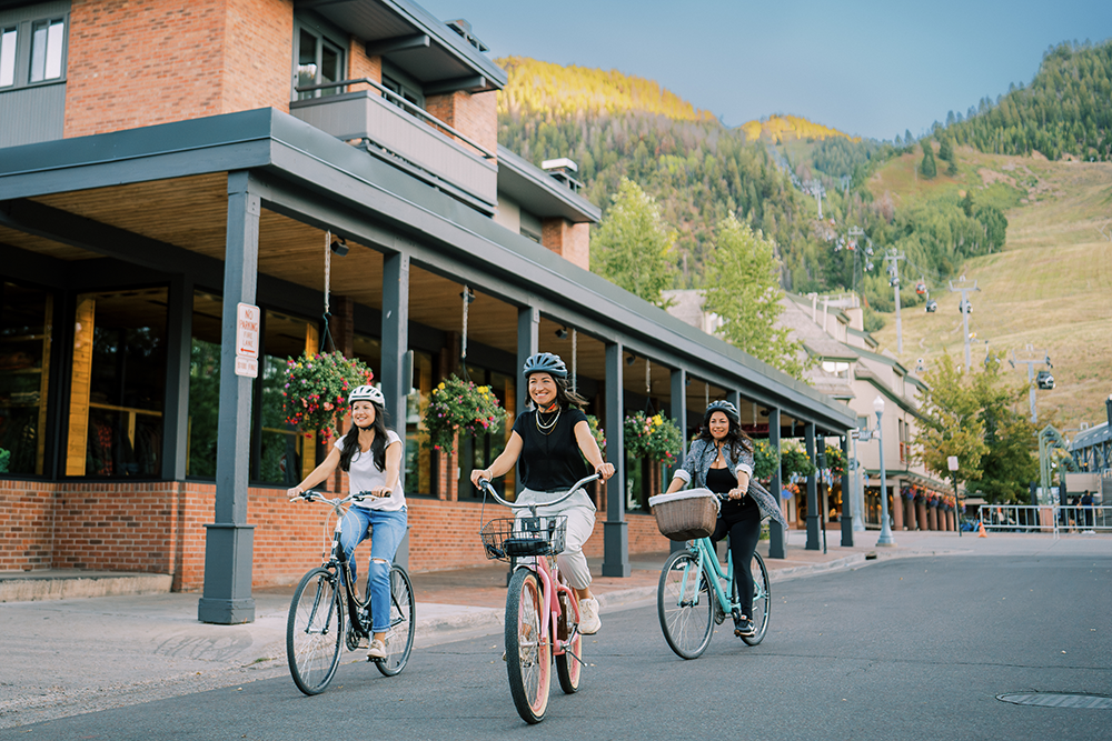 Group of girls biking on a street in downtown Aspen. 