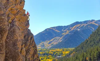 Fall rock climber with Aspen Mountain background